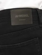 Pantalón jean negro de corte slim fit y tiro medio, con diseño clásico de cinco bolsillos y cierre de cremallera. Confeccionado en tejido de sarga con mezcla de algodón, poliéster, lyocell, viscosa y elastano.