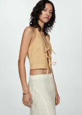 Top corto de cuello halter con cierre frontal mediante lazos decorativos. Presenta un diseño ajustado y sin mangas, confeccionado en una mezcla de fibras naturales.