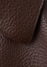 Chaqueta de cuero sintético marrón con cuello camisero, cierre frontal con botones oscuros y bolsillos frontales con solapa.