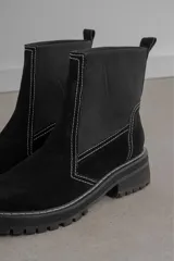 Botas de caña media confeccionadas en gamuza y neopreno, con suela track de goma y costuras a la vista en color blanco.