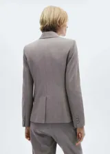 Blazer de corte recto en color beige, con cuello de solapa con muesca, cierre frontal de un botón y bolsillos laterales con solapa. Cuenta con forro interior y mangas largas con puños abotonados.
