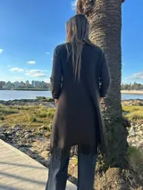 Saco largo marrón con solapa, bolsillos plaqué delanteros y flecos en el ruedo.