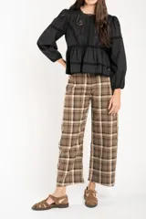 Pantalón de corte recto y tiro medio con estampado de cuadros escoceses en tonos marrones y beige. Presenta cierre frontal con botón y bolsillos laterales.