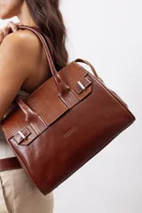 Cartera de mano estructurada de cuero vacuno rojo, con doble asa superior y detalles de charol en la parte superior. Cuenta con cierres metálicos y apliques decorativos laterales con hebillas.