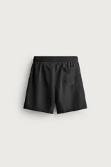 Short de baño largo en color beige, confeccionado en tejido técnico con tacto aterciopelado. Cuenta con cintura elástica ajustable con cordón, bolsillos laterales y detalle de bolsillo trasero, además de forro interior.