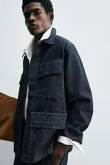 Chaqueta de denim de algodón en color azul oscuro, con corte relajado, cuello solapa, manga larga y cuatro bolsillos frontales con solapa. Presenta cierre frontal oculto por solapa.