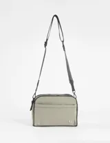 Bandolera de diseño rectangular en color verde oliva, con doble compartimento principal con cierre, bolsillo frontal abierto y correa ajustable extraíble. Presenta detalles de ribetes en color negro y logo metálico en la parte inferior.