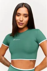 Top corto deportivo verde oscuro con ribetes blancos en el cuello, mangas y dobladillo inferior, con pequeño estampado tipográfico en el pecho.