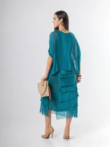 Vestido midi de seda italiana color negro, diseño dos en uno con capa superior de calce amplio, falda con volados y forro interior de algodón elastizado.