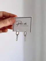 Aros de argolla con dije colgante en forma de símbolo de infinito, confeccionados en acero quirúrgico.