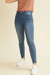 Pantalón jean chupín de tiro alto, color azul, con diseño clásico de cinco bolsillos y cierre frontal con botón y cremallera.