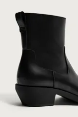 Bota cowboy de cuero color negro, con punta cuadrada, tacón bajo y tirador trasero.