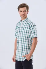 Camisa de manga corta a cuadros en tonos blanco, azul y gris, con cuello abotonado, bolsillo en el pecho y cierre frontal con botones.