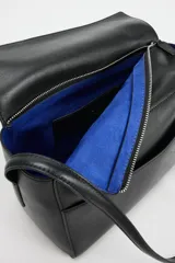 Bolso de hombro de piel color negro, con diseño estructurado, solapa superior y correa ajustable para el hombro.