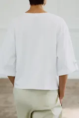 Camiseta de algodón con cuello redondo, manga tres cuartos con detalle de botón metálico y bajo recto.