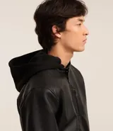 Campera negra de cuero sintético con cuello mao, cierre frontal con cremallera y bolsillo vertical con cremallera en el pecho.