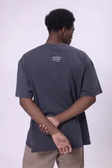 Camiseta de manga corta, color gris oscuro con efecto lavado, corte oversize y cuello redondo. Presenta un pequeño estampado en el pecho con el texto "CREW MEMBER" en blanco.