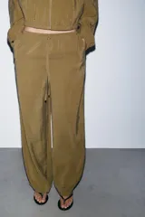 Pantalón tipo palazzo de corte recto y tejido fluido, color naranja. Presenta cintura elástica con cordón ajustable y bolsillos laterales.