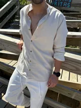 Camisa de cuello mao en color beige, confeccionada en tejido símil lino, con mangas largas y cierre frontal de botones.