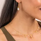 Collar dorado con cadena fina y dijes colgantes de perlas barrocas y piezas irregulares con textura.