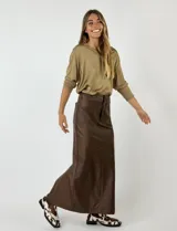 Falda midi color plateado metalizado, de corte recto con tajo en la espalda. Presenta detalles de costura que simulan bolsillos traseros.