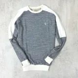 Buzo gris con mangas ranglan blancas y logo bordado en el pecho.