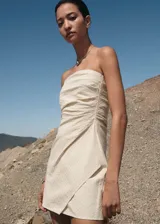 Vestido corto tipo palabra de honor, con diseño recto y drapeado. Presenta una textura con patrón de rayas en relieve y cierre de cremallera invisible en el lateral.