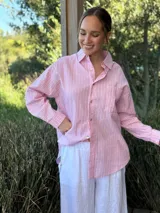 Camisa celeste a rayas verticales blancas, de corte holgado, manga larga y cuello camisero.