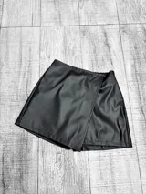 Short pollera negro de efecto cuero, con diseño cruzado en el frente y cintura alta.