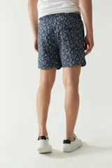 Short de baño color mostaza con estampado floral en azul marino. Cuenta con cintura elástica con cordón de ajuste, dos bolsillos laterales y uno trasero.