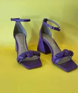 Sandalias de cuero color violeta con textura tipo cocodrilo, taco geométrico y pulsera al tobillo.