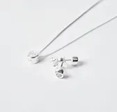 Set de joyería compuesto por collar con dije de punto de luz y par de caravanas a juego, confeccionados en plata 925 con engaste de circonias.