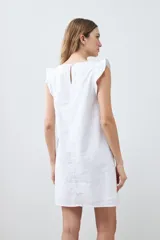 Vestido corto blanco de lino, sin mangas, con volados en los hombros y escote redondo.