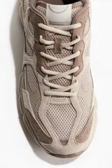 Championes deportivos en malla y tejido revestido con cierre de cordones, diseño con suela gruesa en tonos marrón y beige.