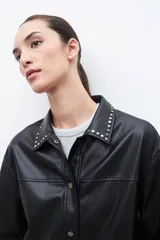 Sobrecamisa negra de cuero sintético con cuello camisero y tachas plateadas.