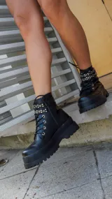 Borcegos negros de cuero sintético con plataforma y cordones. Presentan una tira con apliques metálicos alrededor del tobillo y cierre lateral con cremallera.