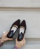 Mocasines de cuero color marrón chocolate, con punta fina y tira sobre el empeine con hebilla metálica.