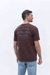 Remera de manga corta color marrón, con cuello redondo y calce regular. Presenta un estampado en la espalda con lettering en tonos claros que incluye la frase 'Torino's Perfomance Authen-tech Research lab' y el logo de la marca Brooksfield.