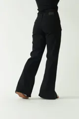 Pantalón negro de tiro medio, corte ajustado en la cadera y piernas que se ensanchan. Presenta cortes en el bajo de cada pierna.