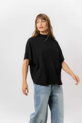 Sweater de tejido de punto color negro, con cuello semi alto y mangas cortas amplias. Presenta una silueta relajada y caída fluida.