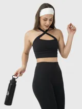 Top deportivo negro con diseño de cuello halter y tirantes cruzados en la parte frontal. Cuenta con sujetador integrado y almohadillas removibles, ofreciendo soporte medio.