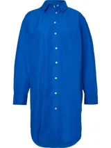 Vestido camisero de corte oversize confeccionado en algodón orgánico. Presenta cuello inglés, cierre frontal de botones, mangas largas con puños abotonados y largo hasta la rodilla. Incluye el logo de la marca bordado en uno de los puños.