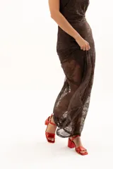 Vestido largo de encaje color chocolate, con escote halter y diseño ajustado en el torso que se abre en una falda con transparencia en el ruedo.