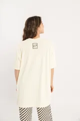 Remerón color crema de tejido acanalado, con cuello redondo, mangas cortas y tajos laterales.