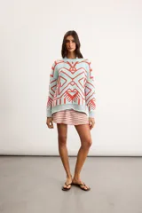 Buzo oversize de punto color marfil con diseño geométrico jacquard en tonos rosado, amarillo, celeste y marrón. Cuenta con cuello redondo y mangas largas.