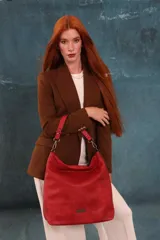 Cartera tipo bandolera de gran tamaño, confeccionada en cuero sintético con acabado desgastado. Cuenta con una asa corta fija, una correa larga regulable y extraíble, y una placa metálica con la marca en la parte frontal.