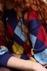 Buzo de tejido de punto con diseño de rombos en colores azul marino, amarillo, celeste y rojo. Presenta cuello redondo a la base, corte oversized y puños acanalados.