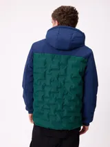 Campera con capucha, diseño bicolor en negro y gris oscuro, con panel frontal acolchado y mangas lisas. Cuenta con cierre frontal, bolsillos laterales y puños elásticos.