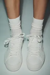 Zapatillas deportivas blancas con detalle de pespuntes a contraste y cordones.