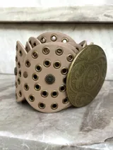 Cinto faja de cuero sintético negro con hebilla metálica dorada con diseño circular calado.